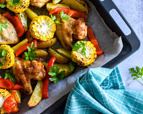 Traybake met kippenvleugels, mais en aardappel